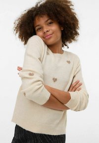 Krémově zbarvený svetr z měkké tkaniny, s kulatým výstřihem, dlouhými rukávy a rozptýlenými hnědými srdíčky na přední straně.