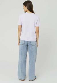 T-shirt lilas à manches courtes associé à un jean large bleu clair. Matériau en coton avec une coupe classique et un col rond.