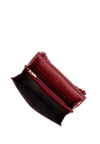 Červená kožená peněženka s lesklým povrchem, s zlatými prvky, zipovou kapsou a několika sloty na karty uvnitř.