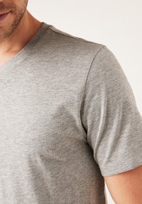 Graues V-Ausschnitt-T-Shirt aus weichem, leichtem Stoff; verfügt über kurze Ärmel und eine glatte Textur mit minimalen Details.