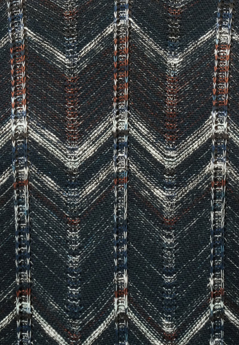 Tissu tissé présentant un motif chevron dans des tons bleu foncé, blanc et rouge, avec une surface texturée et des coutures détaillées.