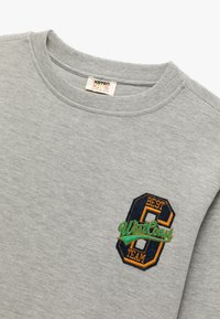 Grå sweatshirt lavet af bomuldsblanding, med ribbet halsudskæring og broderet detalje på venstre bryst med teksten "Bedste 8 West Coast Team."