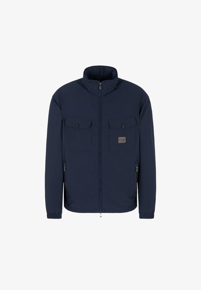 Giacca a zip blu navy con colletto alto, tessuto testurizzato, due tasche sul petto con pattina, tasche laterali con zip e polsini elasticizzati.