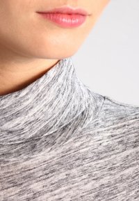 Grauer Pullover mit hohem Kragen und strukturiertem, meliertem Muster. Der Stoff wirkt weich und dehnbar und hat ein tailliertes Design am Hals.