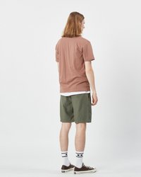 Kortärmad brun skjorta som matchas med gröna shorts. Modellen bär vita strumpor med svarta ränder och bruna sneakers. Enkelt mönster, avslappnad passform.