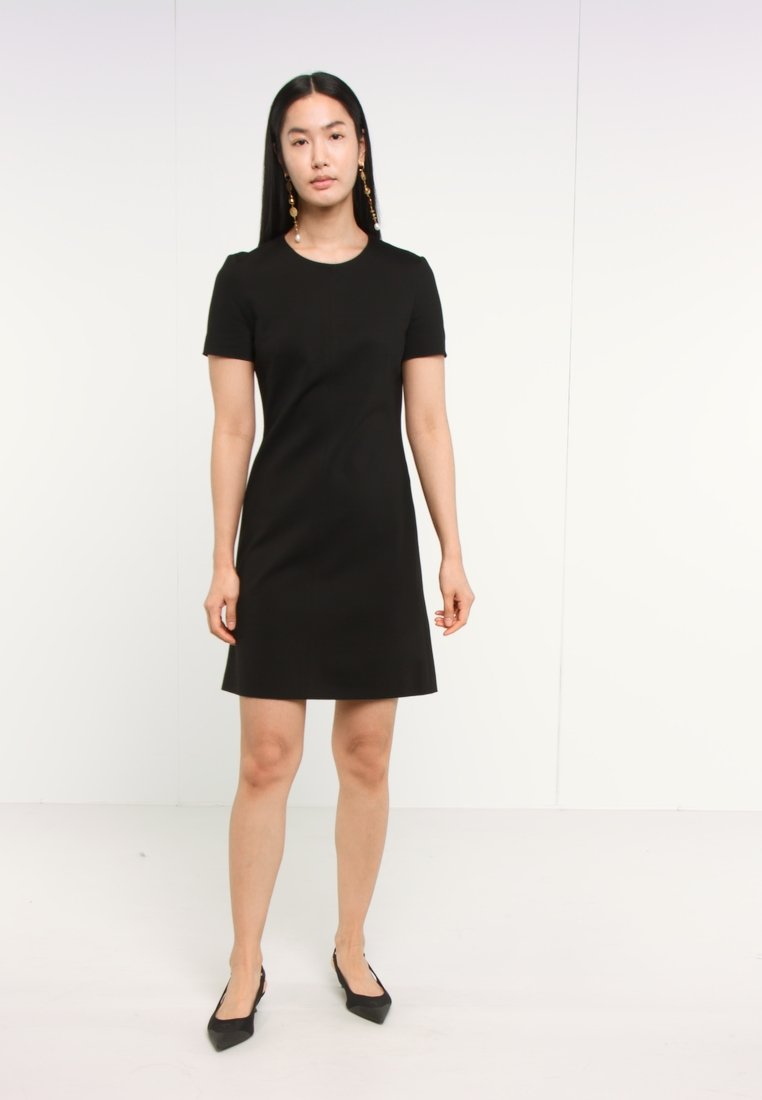 Robe noire à manches courtes avec un design simple en A. Tissu lisse, encolure ronde, ourlet au niveau du genou et coutures discrètes.