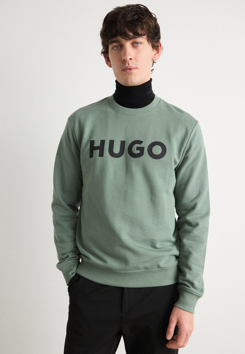 Grønn bomullssweatshirt med rund hals og stor svart "HUGO" tekstlogo foran. Lange ermer med ribbestrikkede mansjetter og kant.