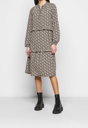 Vestido de manga larga en marrón oscuro con un estampado floral, que presenta una falda en capas y un escote fruncido; combinado con botas de combate negras.