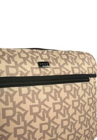 Bolsa de tela beige con un patrón repetido de logo "DKNY" en marrón oscuro, con un zipper negro y cinta de zipper a juego. Textura suave.