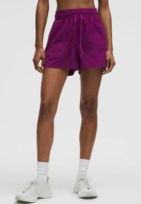 Pantalones cortos deportivos morados con un acabado texturizado, cinturilla elástica y cordón. Cuenta con dos bolsillos laterales y un ajuste holgado.