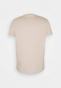Camiseta beige de manga corta con cuello redondo, hecha de material de algodón suave. Textura lisa, sin patrones ni acentos visibles.