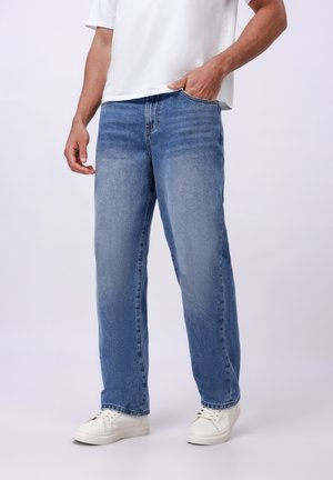 Light blue denim jeans with a straight-leg cut, featuring subtle fading and five pockets. Paired with white sneakers.