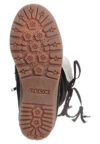 Botte en daim noir avec une semelle en caoutchouc marron, présentant des motifs de bande de roulement en forme d'étoile et une doublure blanche douce. Comprend des lacets décoratifs noirs.