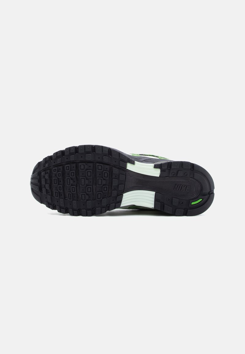Semelle de chaussure Nike noire et blanche avec motif antidérapant texturé, accents verts et marquage "Nike" et "Air" en dessous.