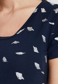 Navy cotton t-shirt with a scoop neckline and short sleeves, featuring abstract silver print throughout on a smooth texture.