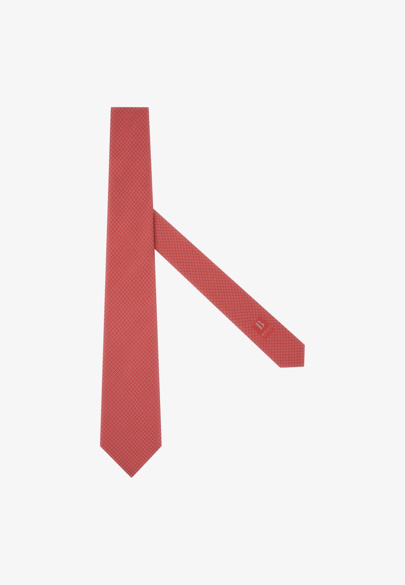 Červená kravata s texturovaným geometrickým vzorem, úzkého tvaru a s špičatými konci; má malou logo nášivku nedaleko konce úzkého hrotu.