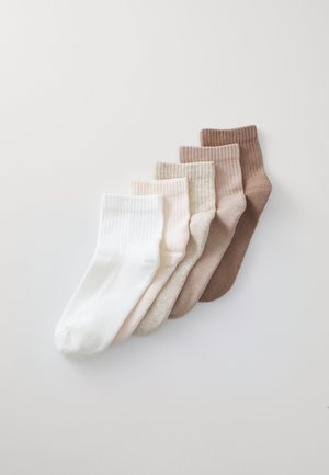 Puuvillapaitoja viidessä värissä: valkoinen, vaaleanbeige, beige, taupe ja ruskea. Varressa on ribbireuna ja pehmeä tekstuuri.