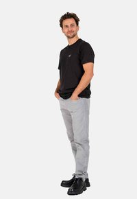 Black short-sleeve t-shirt, gray slim-fit pants, and black lace-up boots; displayed against a plain white background.