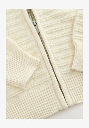 Maglione zip-up crema con un design a coste texturizzato, polsini strutturati e una robusta cerniera metallica sul davanti.