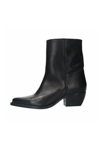 Bottine en cuir noir avec un bout pointu et un petit talon empilé, présentant une texture lisse et un design minimaliste.