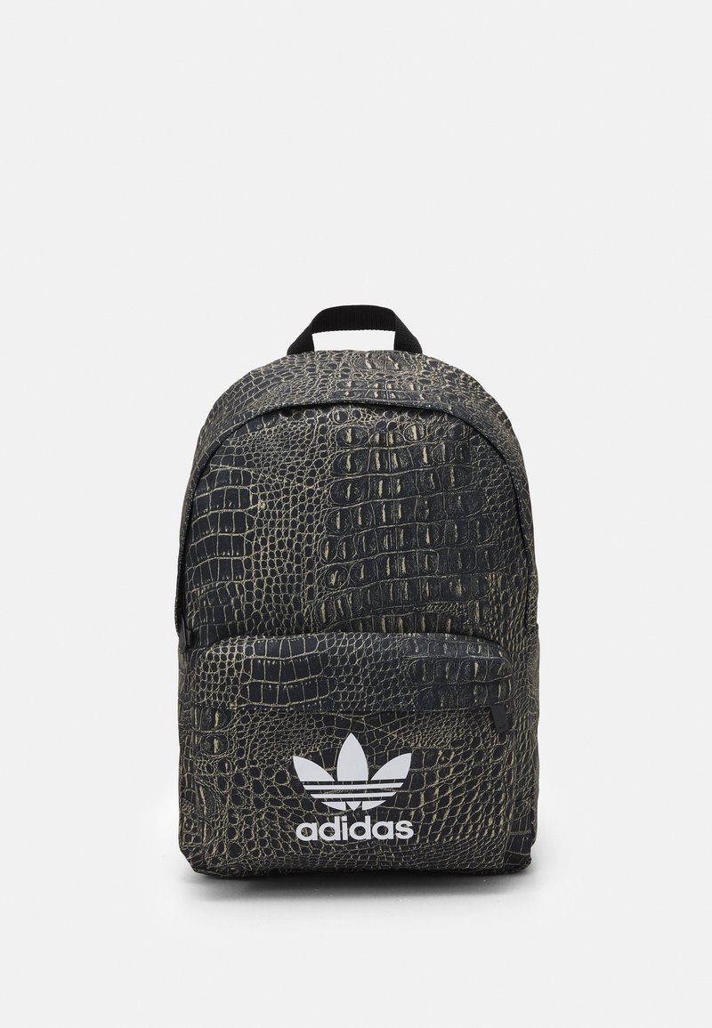 Zwarte rugzak met krokodillenpatroon, voorzien van een voorzak met rits en een wit Adidas-logo. Is uitgerust met een handvat aan de bovenkant en gepolsterde schouderbanden.