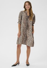 Šaty s leopardím vzorom v svetlo béžovej a čiernej farbe. Majú výstrih do V, nafúknuté rukávy a končia tesne nad kolenami. Jemná látka s voľným strihom.