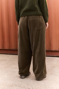 Wide-leg corduroy trousers in olive green with a textured vertical stripe pattern. Features a back pocket and a relaxed fit.