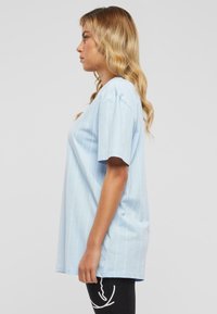 Hellblau gestreiftes T-Shirt mit kurzen Ärmeln, lockerer Passform und weichem Baumwollstoff. Horizontale weiße Streifen schaffen ein dezentes Muster.