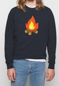 Marinblå sweatshirt med ett motiv av en lägereld med orange lågor och bruna stockar, tillverkad av mjukt material med ribbade mudd och nederkant.