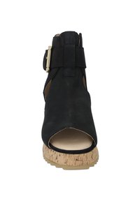 Black leather open-toe sandal with a cork heel. Features a strap with metallic hardware and cut-out design on the sides for ventilation.