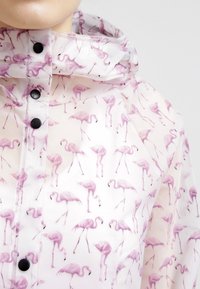 Transparent plastregnrock med ett mönster av rosa flamingos, med dragkedja fram, svarta knappar och justerbar huva.