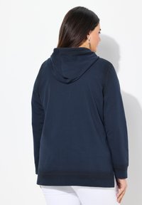 Sweat à capuche bleu marine avec une coupe décontractée, en tissu doux, poche kangourou et poignets côtelés. Caractéristiques : ourlet droit et fentes latérales.