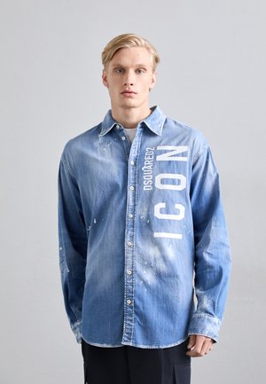 Džínová košile světlé modré barvy s vybledlým vzhledem, obsahující bílý grafický nápis "DSQUARED2 ICON" a knoflíkovou légu, dlouhé rukávy.