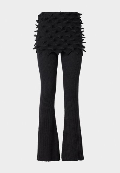 Czarne, prążkowane spodnie ze rozszerzanymi nogawkami, z teksturowanym, warstwowym paskiem w talii, który posiada wypukłe, trójkątne akcenty. Materiał wygląda na dzianinowy i elastyczny.