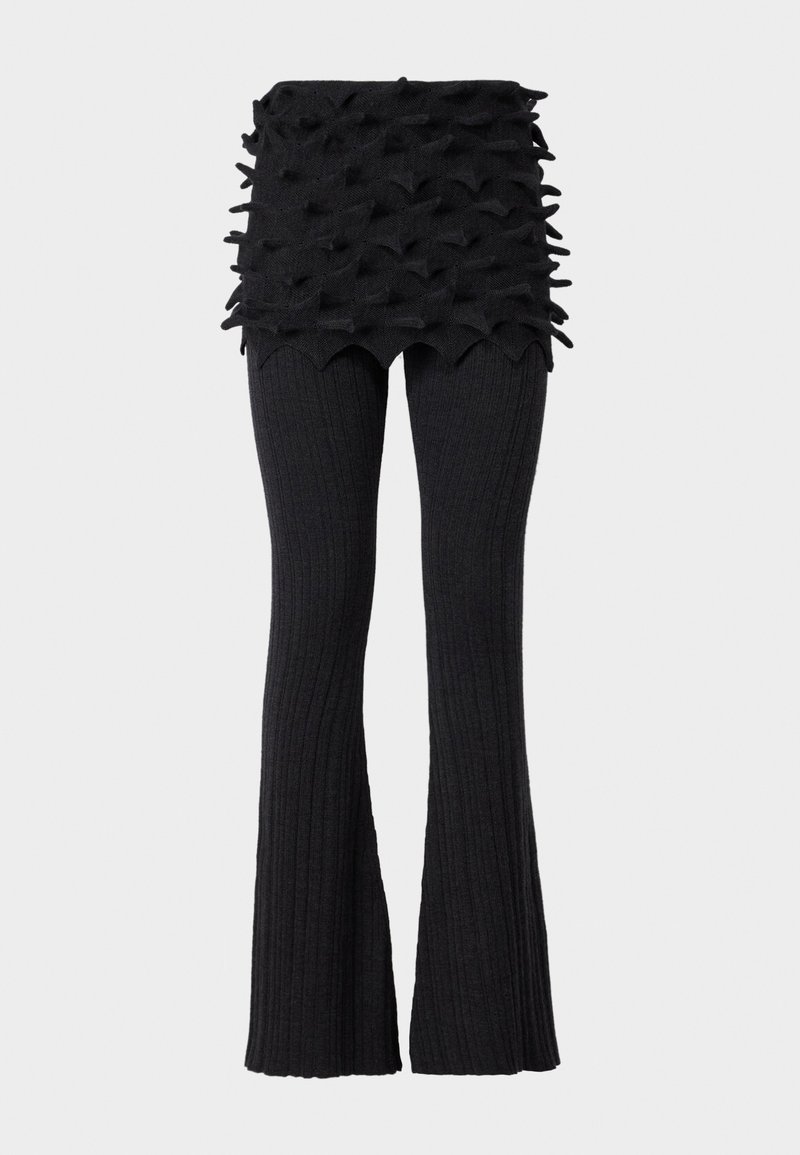 Schwarze gerippte, ausgestellte Hose mit einem strukturierten, geschichteten Bund, der erhabene, dreieckige Akzente aufweist. Das Material wirkt gestrickt und elastisch.