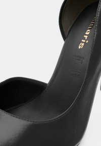 Chaussure à talon haut en cuir noir avec un bout arrondi et une texture lisse. Présente une semelle intérieure marquée du logo et des détails de couture subtils.