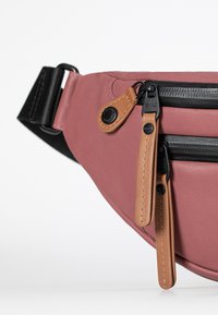 Fanny pack met een roze buitenstof, zwarte ritsen en bruine leren accenten met een gestructureerde oppervlakte en een verstelbare band.