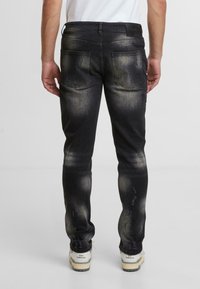 Czarne dżinsy z denimu o wyblakłym wykończeniu, pięcioma kieszeniami i przetarciami. Posiadają kontrastowe szwy oraz wąskie nogawki.