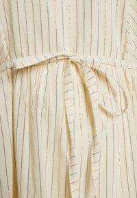 Tessuto giallo chiaro con strisce verticali multicolori. Presenta una vita legata con un design sciolto e fluido e una texture morbida.