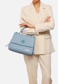 Borsa blu strutturata realizzata in materiale testurizzato. Dotata di una chiusura circolare, tracolla removibile e manico piatto.