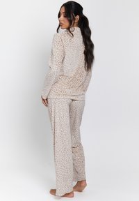 Conjunto de ropa cómoda con estampado de leopardo en beige, que incluye una camiseta de manga larga y pantalones de pierna ancha, con una textura suave y un ajuste relajado.