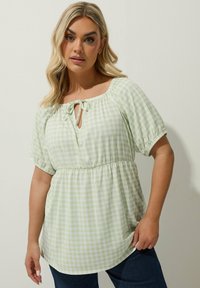 Vihreä ja valkoinen ruudullinen pusero, jossa on pyöreä kaula-aukko, solmuseikka, lyhyet puffihihat ja elastinen vyötärö; rento malli.
