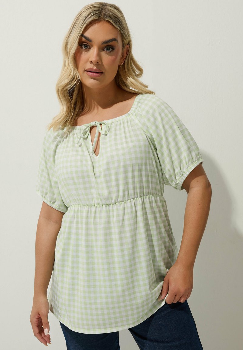 Vihreä ja valkoinen ruudullinen pusero, jossa on pyöreä kaula-aukko, solmuseikka, lyhyet puffihihat ja elastinen vyötärö; rento malli.