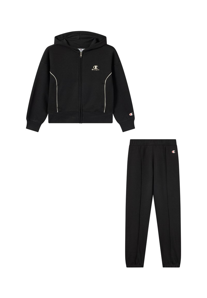 Felpa nera con zip e piping bianco, abbinata a pantaloni della tuta neri con vita elastica e dettagli con logo.