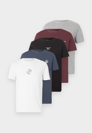 Mann steht und trägt ein weißes T-Shirt mit Grafik, hellblaue Jeans, schwarzen Gürtel und schwarze Schuhe vor weißem Hintergrund