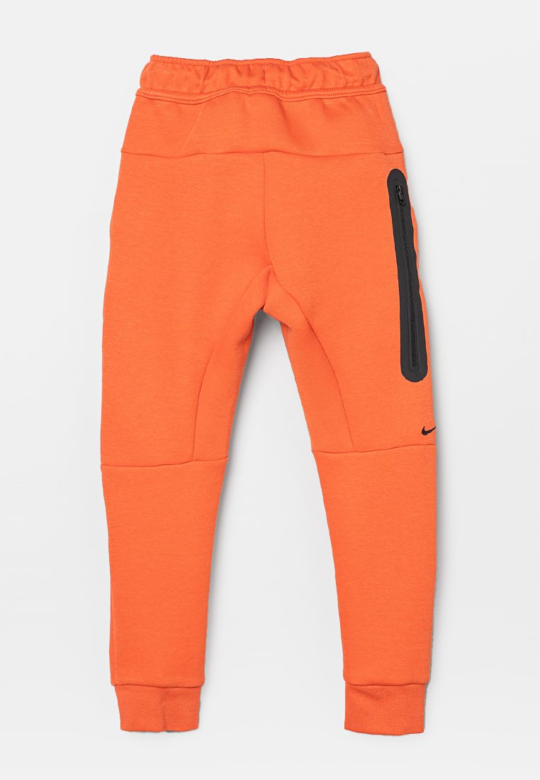 Orange Jogginghose mit elastischem Bund, seitlichem Reißverschlussfach in Schwarz und einem Nike-Logo am linken Bein. Hergestellt aus weichem, strapazierfähigem Stoff.