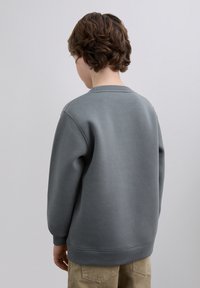 Gray sweatshirt with a textured surface, crew neckline, and ribbed cuffs. Back view showing relaxed fit and minimal design details.