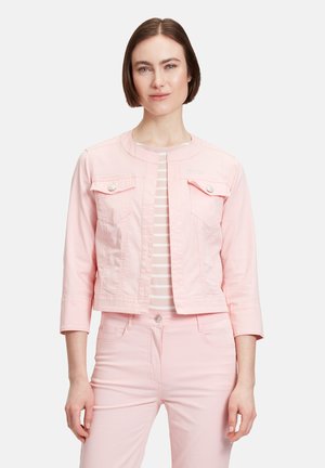 Kurze pinke Jeansjacke mit rundem Ausschnitt, zwei Fronttaschen und silbernen Druckknöpfen. Getragen über einem gestreiften weißen und pinken Oberteil.