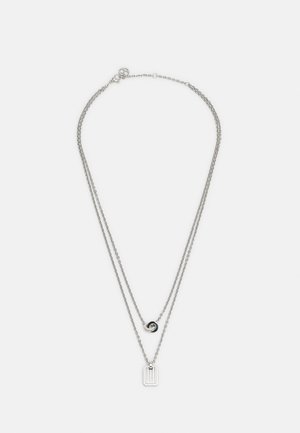 Zilveren dubbel-laags kettinkje met een ronde in elkaar grijpende ringhanger aan de kortere ketting en een rechthoekige staafhanger aan de langere ketting.