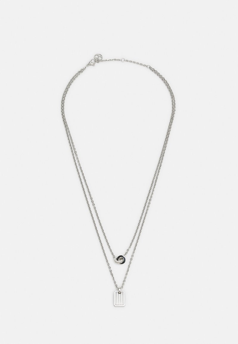 Collier à double chaîne en argent avec un pendentif rond en anneau entrelacé sur la chaîne courte et un pendentif barre rectangulaire sur la chaîne longue.